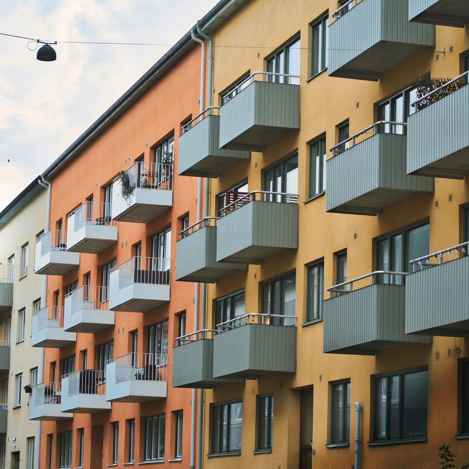 Fasad med balkonger i orange och gult på ett flerbostadshus i Lund.